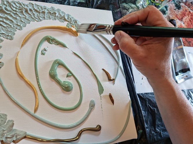 ręka trzymająca pędzel nad obrazem