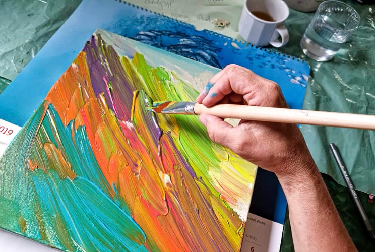 ręka trzymająca pędzel nad obrazem